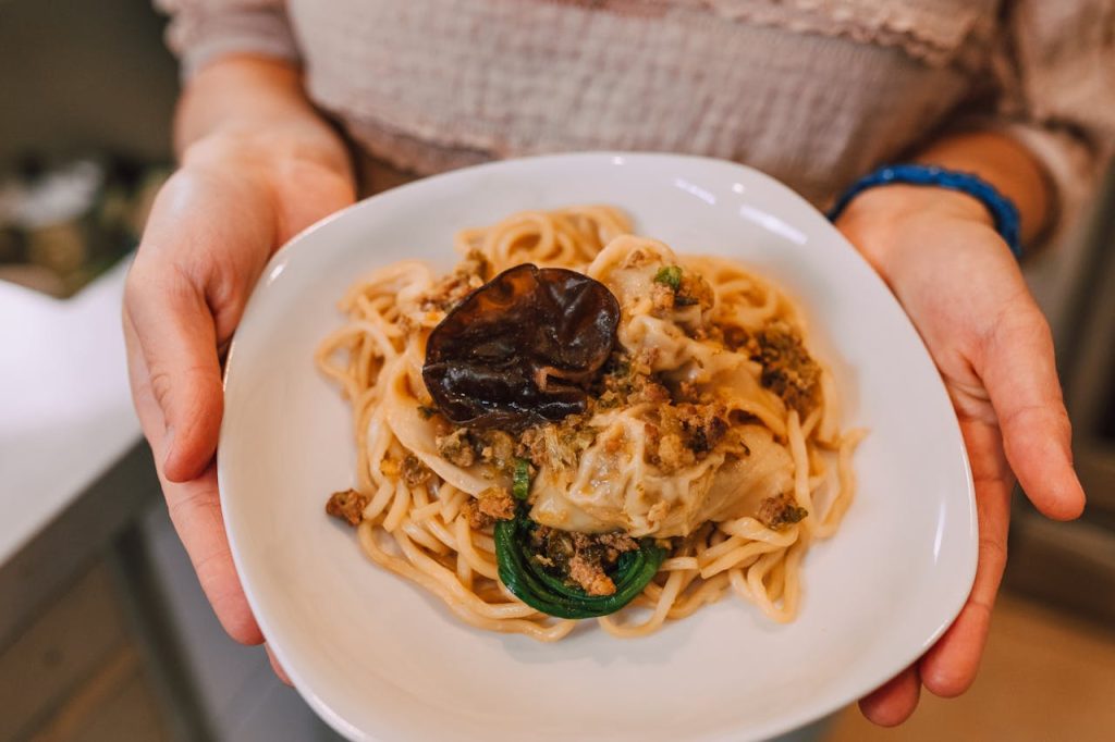 Close-up of creamy pasta with mushrooms, held in hands. Perfect for food photography enthusiasts.